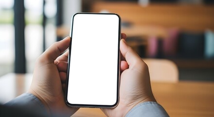 Person Holding a Modern Smartphone with a Blank White Screen Displaying Content in a Brightly Lit Cafe Environment Demonstrating Mobile Device Technology and Connectivity