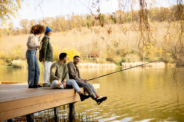 Friends enjoy a relaxing day fishing together on a sunny lake in autumn