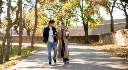 Couple enjoys a leisurely walk in a sunny park during autumn season