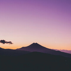 Majestic volcano at sunset, tranquil mood with vibrant purple sky and silhouettes of hills
