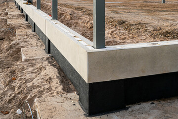 Concrete building foundation with waterproofing layer during early construction stage