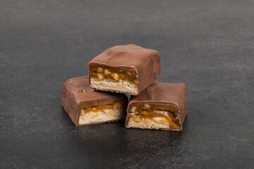 Chocolate bar with nougat, caramel, peanuts and hazelnuts. Dark background. Close up