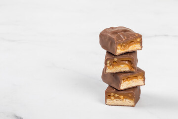Chocolate bar with nougat, caramel, peanuts and hazelnuts. White background. Copy space