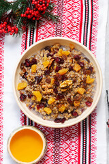 Traditional Christmas Ukrainian wheat kutia with dried fruits, honey and poppy seeds on a Christmas rustic background
