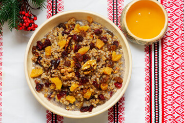 Traditional Christmas Ukrainian wheat kutia with dried fruits, honey and poppy seeds on a Christmas rustic background