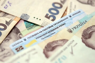 Ukrainian residence permit card or permanent resident card on Ukrainian money close up