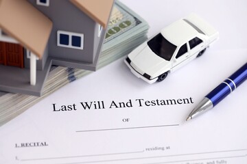 Generic toy house with US dollar bills, car and Last will and testament with pen on table close up