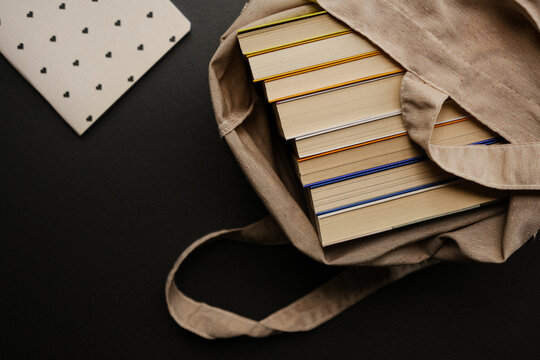 Foto de pilha de livros dentro de bolsa sobre fundo cinza escuro com espa&ccedil;o livre para texto. hobbies. ningu&eacute;m. caderno