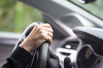 Hand gripping steering wheel of modern vehicle with blurred background and focused details