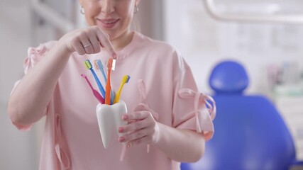 Female dentist holding colorful dental tools in clinic setting.