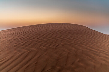 Sand waves on the red dunes in the desert near Dubai at sunrise