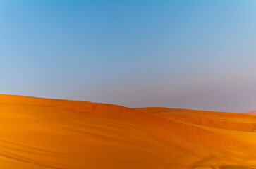 The sun rising on the pristine and untouched red dunes in the desert near Dubai
