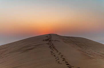 The sun rising on the pristine and untouched red dunes in the desert near Dubai