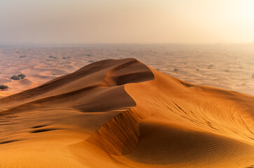 The sun rising on the pristine and untouched red dunes in the desert near Dubai