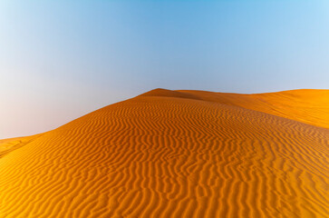 The sun rising on the pristine and untouched red dunes in the desert near Dubai