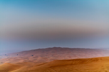 People standing on the red dunes in the desert near Dubai waiting for the sunrise