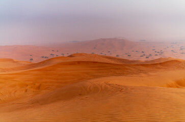 The sun rising on the pristine and untouched red dunes in the desert near Dubai