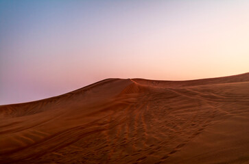 The sun rising on the pristine and untouched red dunes in the desert near Dubai