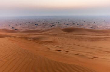 The sun rising on the pristine and untouched red dunes in the desert near Dubai