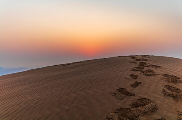 The sun rising on the pristine and untouched red dunes in the desert near Dubai