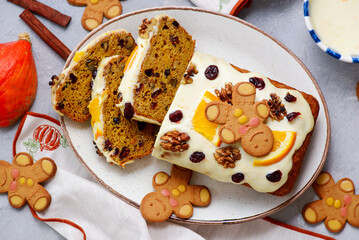 Pumpkin Christmas cake with dried fruits, spices and cheese frosting on a Christmas rustic background