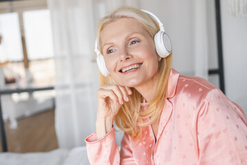 Paid subscription to music podcast streaming e-book application concept. Happy mature woman in headphones, relaxing enjoying carefree weekend time alone at home, stress free leisure.