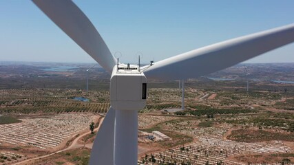 view of frontal nacelle symmetry amidst sunlit fields and distant valleys, closeup of symmetrical nacelle structure with three blades over bright fields and remote access routes