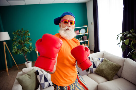 Funny grandpa boxer at home in bright shirt and red gloves