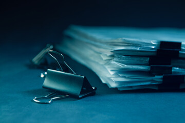 Pile of documents and binder clips on dark blue background.