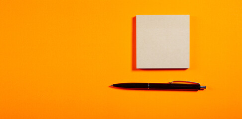 Blank notepad with pen on orange background. Copy space.