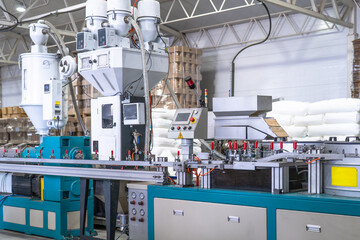 Industrial plastic extrusion machine in modern factory, automated production line with control panel, pneumatic system and material feeders, plastic processing equipment for manufacturing.