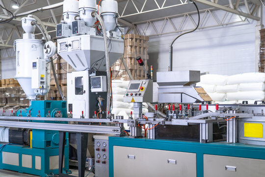 Industrial plastic extrusion machine in modern factory, automated production line with control panel, pneumatic system and material feeders, plastic processing equipment for manufacturing.