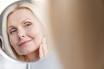Beauty, reflection and mirror with aged woman in bathroom for morning routine, makeup grooming....