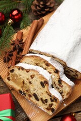 Traditional Christmas Stollen with icing sugar, spices and festive decor on wooden table, flat lay