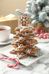 Christmas tree made of gingerbread cookies and candy cane on white marble table