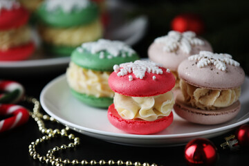 Tasty macarons and Christmas decor on black table, closeup