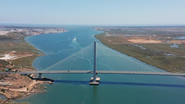 Aerial view of Guadiana International Bridge spanning across river between Portugal and Spain with clear cable-stayed design wetlands and towns visible in background Concept of cross-border 
