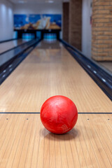 Bowling center with lanes and colorful bowling balls. Entertainment center. Board game. Red bowling ball on the lane