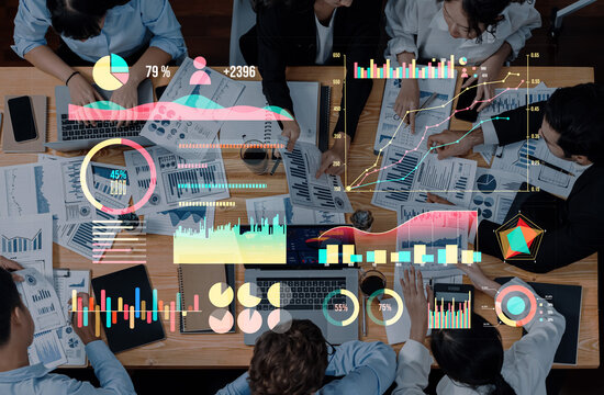 A diverse team engages in data analysis and business strategy discussion, utilizing digital charts and graphs to enhance productivity and collaboration in a modern office. Axiom