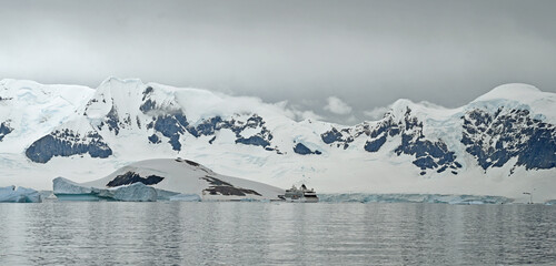 A crusie ship appears as a tiny boat in the Antarctic landscape.
