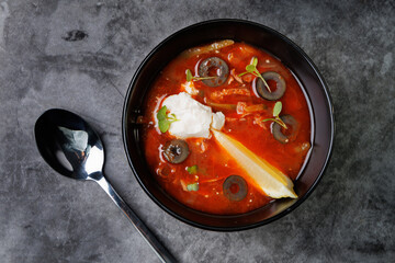 Red Tomato Soup In Black Bowl With Olive Slices, Cream