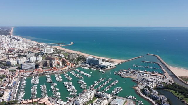 Vilamoura aerial view aerial view vilamoura coastal curve with extensive sandy beach, marina inlet, rows of moored yachts and shimmering turquoise sea stretching to horizon under clear sky