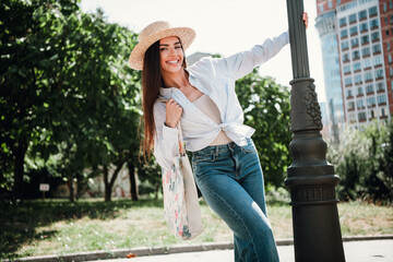 Sunny city stroll with a chic hat tote and jeans female traveler feeling joyful and stylish in vibrant park vibe