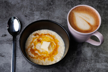 Creamy Oatmeal Breakfast Bowl With Butter, Syrup, And A Cup Of Coffee In A Pink Mug