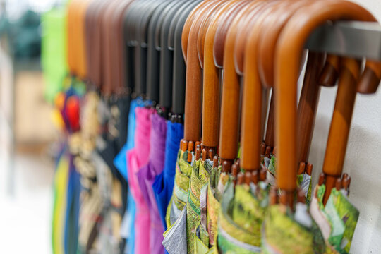 Rainy day rainbow a lineup of colorful closed umbrellas with wooden handles on display at a shop - Powered by Adobe