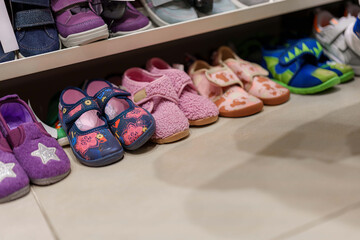 Row of children's shoes lined up on a store shelf showcasing different styles and colors