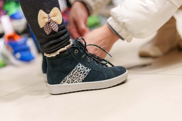 Tying up new shoes in children's shoe store, a family moment of purchase
