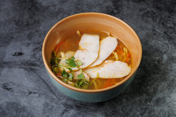 Wholesome Chicken Noodle Soup in Ceramic Bowl With Fresh Greens and Carrot Garnish