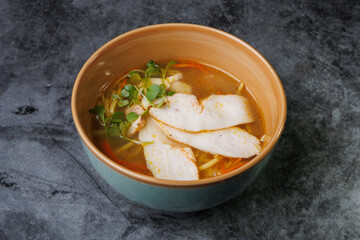 Wholesome Chicken Noodle Soup in Ceramic Bowl With Fresh Greens and Carrot Garnish