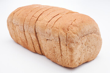 A small, freshly baked loaf of Jamaican sliced whole wheat bread isolated on a white background